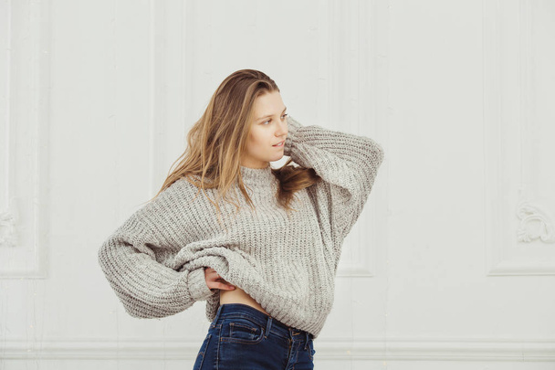 Profile view on women in shapeless sweater standing near wall - Photo, image