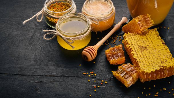A set of honey and bee products. Honey in honeycomb. On a black wooden background. Free space for text. Top view. - Φωτογραφία, εικόνα