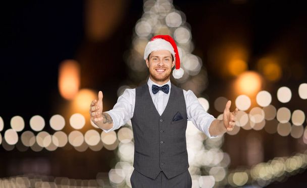 happy man in santa hat holding something imaginary - Foto, Bild