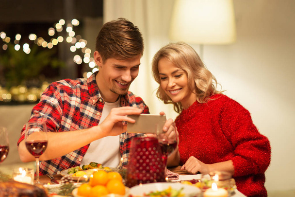couple with smartphone at home christmas dinner - Фото, изображение