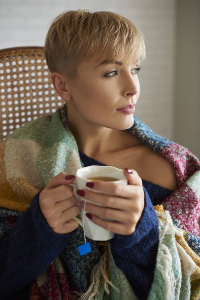 Γυναίκα, τυλιγμένη σε μια κουβέρτα, πίνοντας ζεστό τσάι - Φωτογραφία, εικόνα