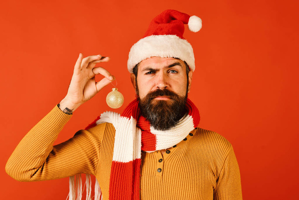 Santa Claus holds golden ball for tree on red background - Foto, afbeelding