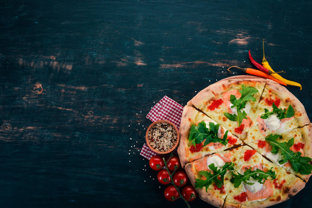Pizza with salmon and caviar. Seafood. Italian cuisine. On a wooden background. Free space for text. Top view. - Foto, Bild