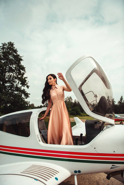 brunette woman in romantic evening dress plane standing in airplane  - Foto, Imagen