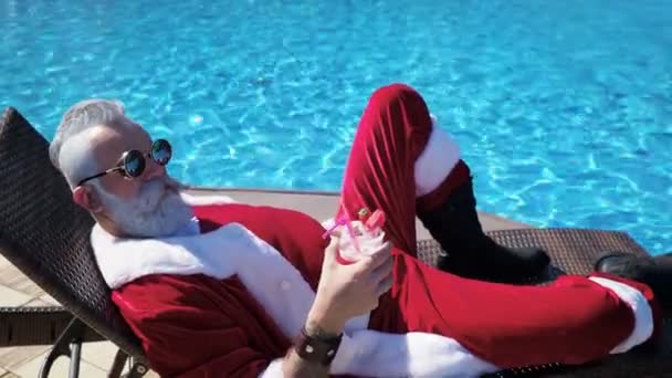 Man in Santa kostuum ontspanning op chaise bij zwembad - Video