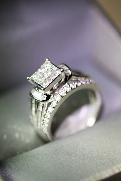 Un anello di fidanzamento diamantato in una scatola con bagliore / riflesso. Brillanti diamanti taglio principessa
. - Foto, immagini
