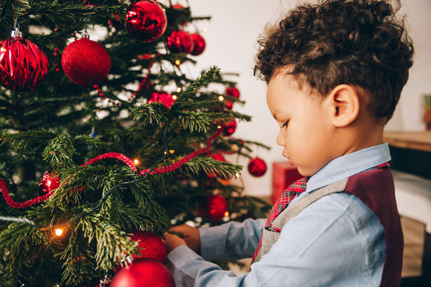 Adorable niño de 3 años decorando el árbol de Navidad
 - Foto, Imagen