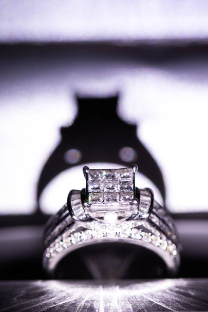 Un anillo de compromiso de diamante en una caja con brillo / reflexión. Diamantes brillantes talla princesa
. - Foto, imagen