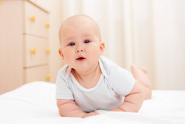 Portrait of beautiful child crawling on the bed at home. Baby care concept. - 写真・画像