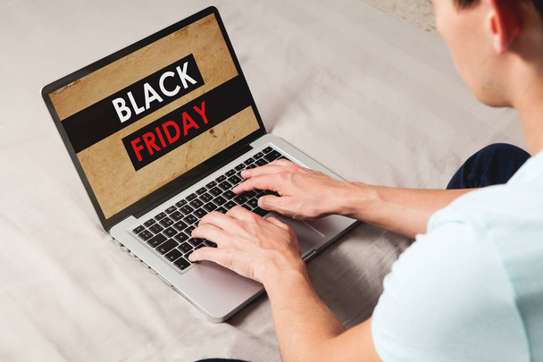 Man shopping at Black Friday special by the internet with a laptop while sitting at home. - Foto, Imagem