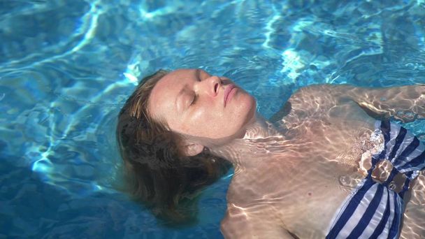 Молодая красивая лежащая женщина в купальнике лежит в воде на открытом воздухе
. - Фото, изображение