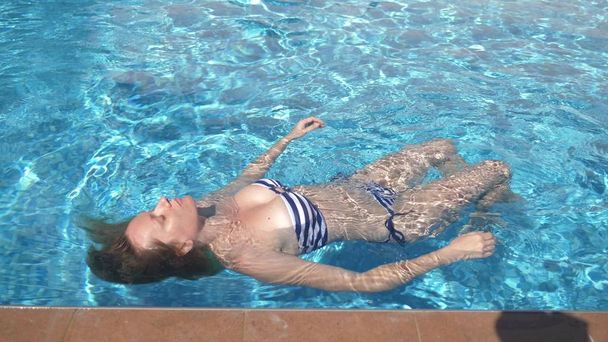 Młoda piękna kobieta leżącej w kostiumie kąpielowym, leżąc w wodzie na zewnątrz. - Zdjęcie, obraz