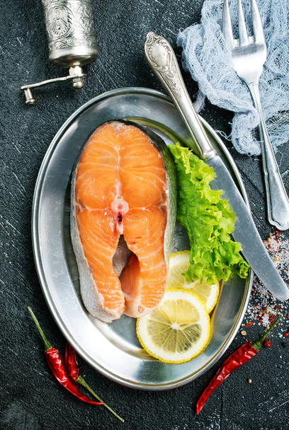raw salmon slice with lemon and greens on metal plate on table - Фото, зображення