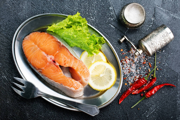 raw salmon slice with lemon and greens on metal plate on table - Φωτογραφία, εικόνα
