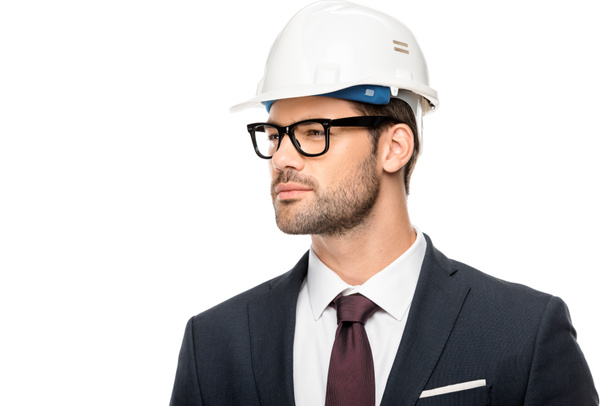 zeker jonge mannelijke architect in brillen en helm op zoek weg op wit wordt geïsoleerd  - Foto, afbeelding