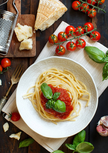 Spaghetti pasta with tomato sauce, basil and cheese on a wooden table - Foto, immagini