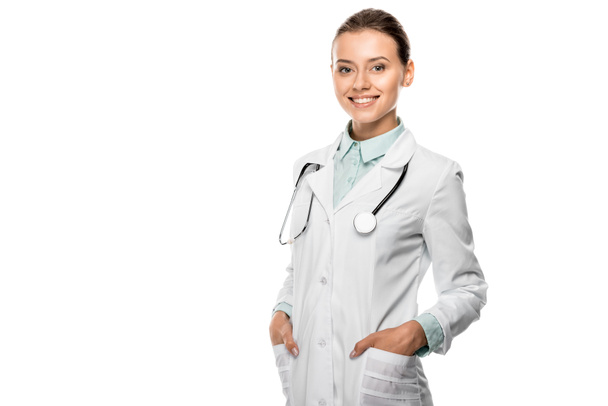 cheerful young female doctor with stethoscope over neck looking at camera isolated on white - Photo, Image