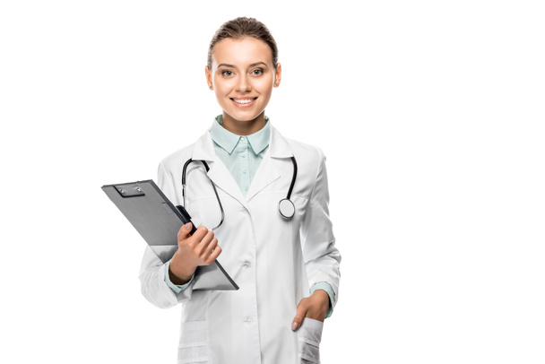 joyeuse jeune femme médecin en manteau médical tenant presse-papiers isolé sur blanc
 - Photo, image