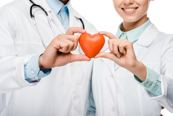 zugeschnittenes Bild junger Ärzte in Arztkitteln, das Herzsymbol isoliert auf Weiß zeigt - Foto, Bild