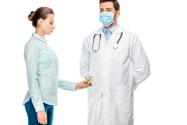 vista lateral de paciente femenino poniendo soborno en bolsillo de joven médico masculino aislado en blanco
 - Foto, Imagen