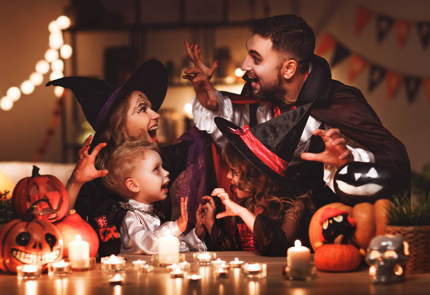 счастливая семья мать отец и дети в костюмах и макияж на празднование Хэллоуина в темном доме
 - Фото, изображение