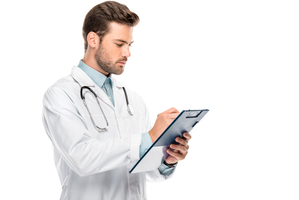 side view of male doctor with stethoscope over neck writing in clipboard isolated on white - Photo, Image