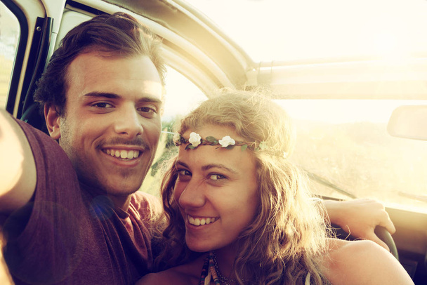Happy young couple in a car enjoying the beautiful sunset in countryside. - Photo, image