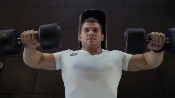 Strong guy makes exercises with dumbbells in the gym - Filmagem, Vídeo