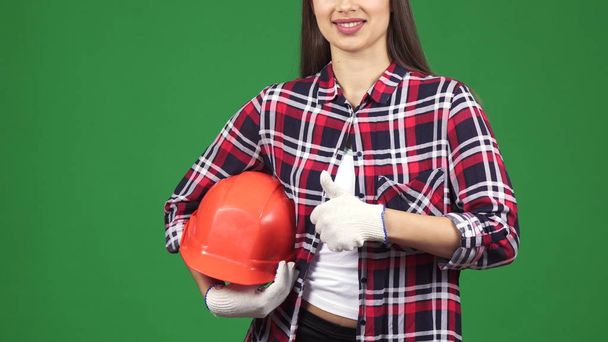 Oříznout záběr usmívající se žena inženýra ukazující thimbs drží bezpečnostní přilba - Fotografie, Obrázek