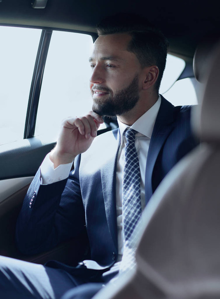 Smiling business man sitting in the back seat of a car - Фото, зображення