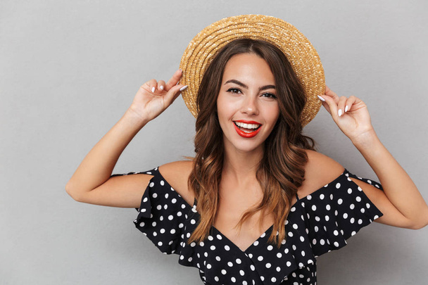 Image of cheerful young cute woman wearing hat looking camera over grey wall. - 写真・画像