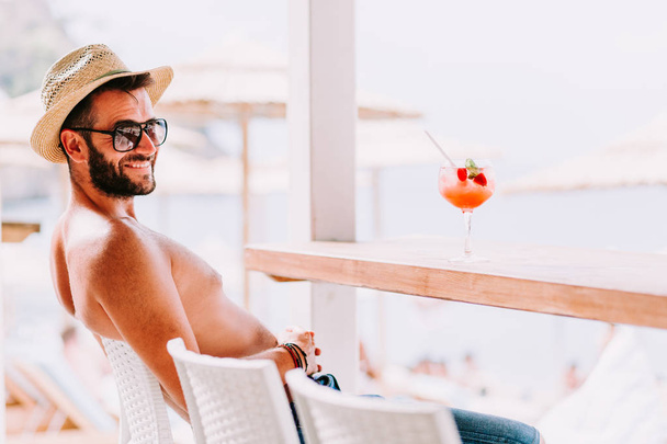 Young man enjoying cocktail in a beach bar - Photo, Image