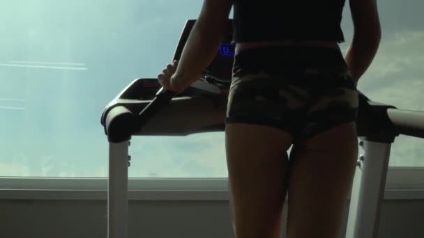 Beautiful young girl on a treadmill in the gym - Video