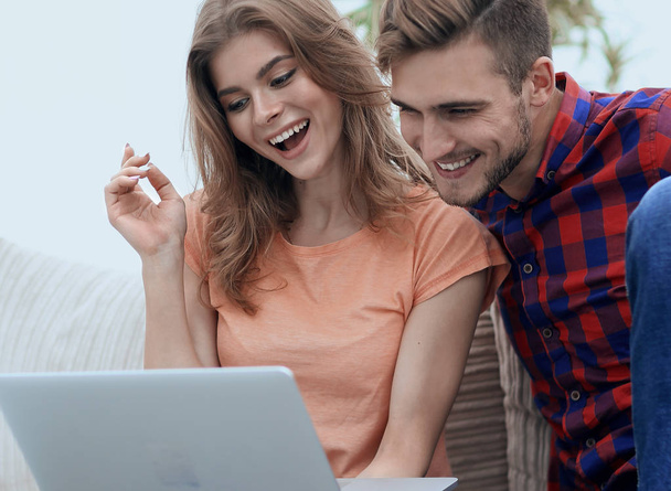 young man with his girlfriend looking at the laptop sitting on t - Foto, Imagen