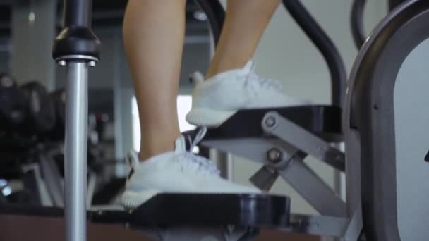 Beautiful young girl on the simulator in the gym - Filmagem, Vídeo