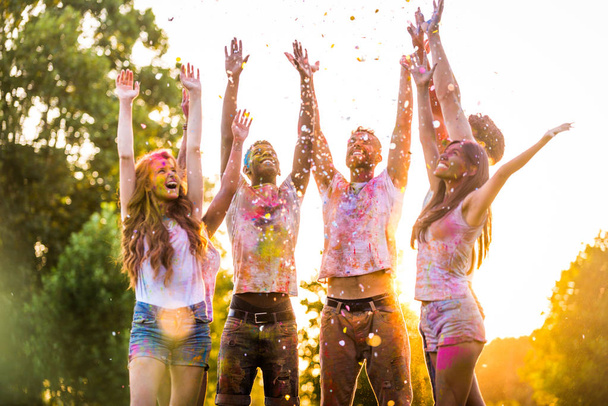 Group of happy friends playing with holi colors in a park - Young adults having fun at a holi festival, concepts about fun, fun and young generation - Фото, изображение