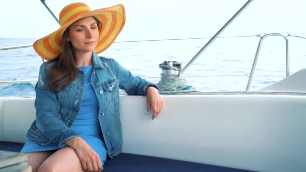 Žena ve žlutém klobouku a modré šaty dívka spočívá na palubě jachty na letní sezónu v oceánu - Záběry, video