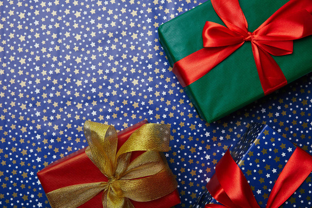yıldız desenli kağıt ambalaj üzerinde şeritler ile sarılmış hediyeler ile düz lay - Fotoğraf, Görsel