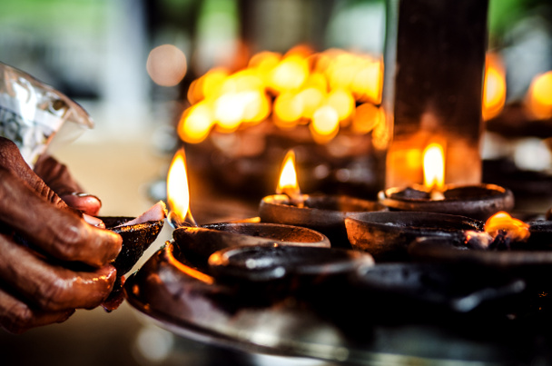 Верующий зажигает свечу в буддийском храме. Шри-Ланка
. - Фото, изображение