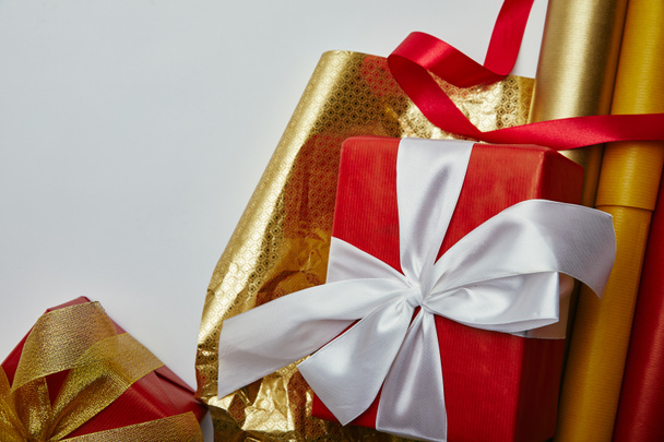 flache Lage mit verpackten Weihnachtsgeschenken, Bändern und Geschenkpapier auf weißem Hintergrund - Foto, Bild