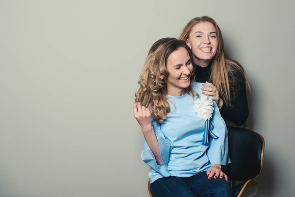 Two laughing female friends, isolated on grey backround. Copy space. Women fashion. Friendship, lifestyle, people and fashion concept. Girl friends have fun together at studio - Foto, imagen