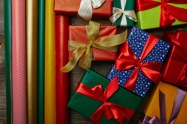 Ansicht von oben nach Anordnung verschiedener Geschenkpapiere und Neujahrsgeschenke mit Bändern auf Holztischplatte - Foto, Bild