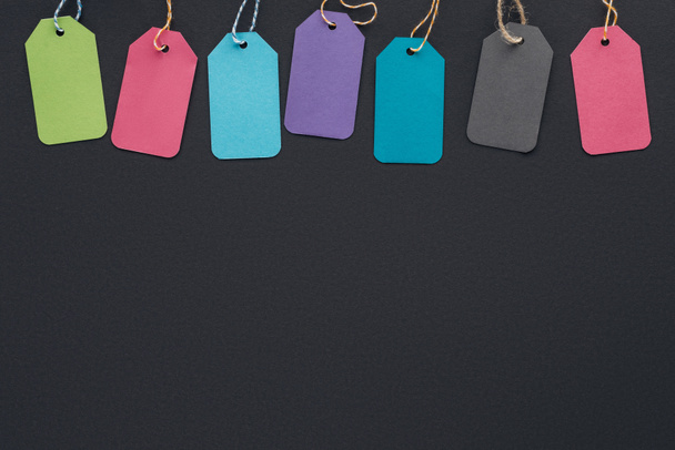 top view of colorful sale tags on black background with copy space for black friday   - Photo, Image