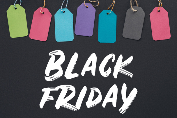 Draufsicht auf bunte Verkaufsetiketten auf schwarzem Hintergrund mit schwarzem Freitag-Schriftzug - Foto, Bild