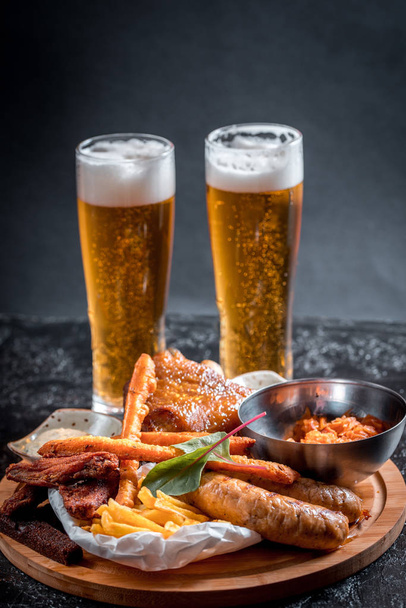 Foamy beer in a glass, hot appetizer, chicken wings, sauce in a beautiful served bowl. Catrofel and other deep-fried vegetables. unhealthy food. unhealthy food. many calories - Foto, Imagem