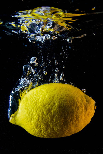 Lemon in water on a black background - Φωτογραφία, εικόνα