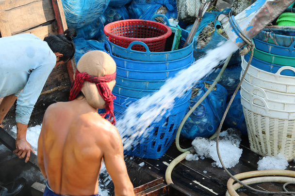 Fischer warten auf den Fischerbooten in Thailand auf das Entladen von Eis für gefrorenen Fisch. - Foto, Bild