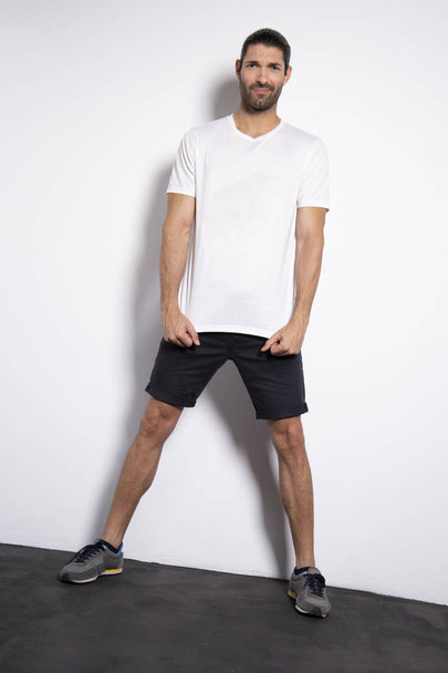Attractive caucassian young man with brown hair on white background with natural shadow.  Studio sport session. Copy space T-shirt - Foto, immagini