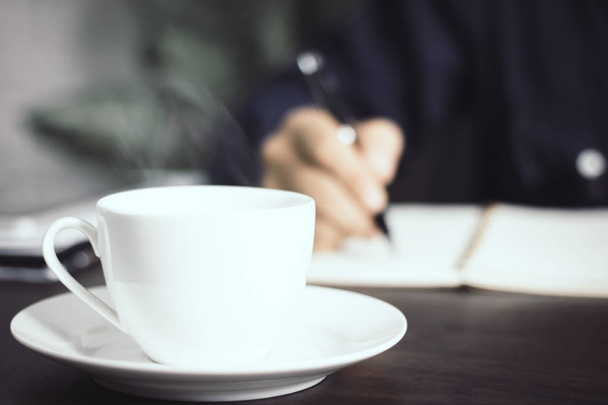 Close up cup of coffee on manager or business man signing contract background , lawyer writing on paper concept - Photo, image
