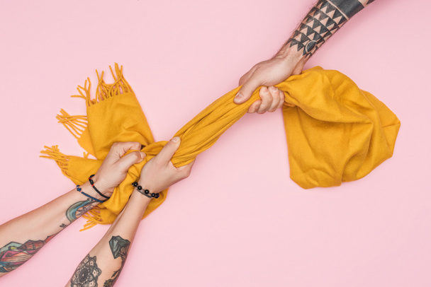 Teilansicht tätowierter Shopaholics, die gelben Schal isoliert auf rosa ziehen - Foto, Bild